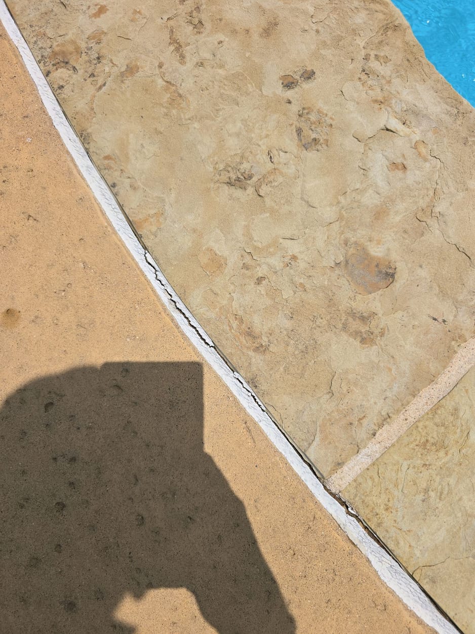 Cracked and separating sealant at the joint between pool coping and the pool deck, documented on a North Texas pool inspection