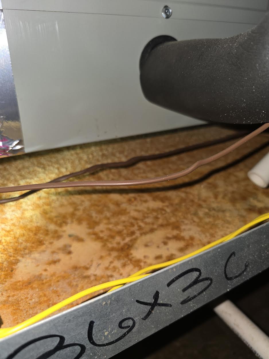 Rusted HVAC secondary drain pan from a clogged condensate line, found in Prosper, TX
